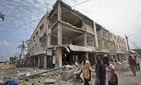Men walk near destroyed buildings as thousands of Somalis gathered to pray at the site of the country's deadliest attack and to mourn the hundreds of victims, at the site of the attack in Mogadishu, Somalia Friday, Oct. 20, 2017. Men walk near destroyed buildings as thousands of Somalis gathered to pray at the site of the country's deadliest attack and to mourn the hundreds of victims, at the site of the attack in Mogadishu, Somalia Friday, Oct. 20, 2017.