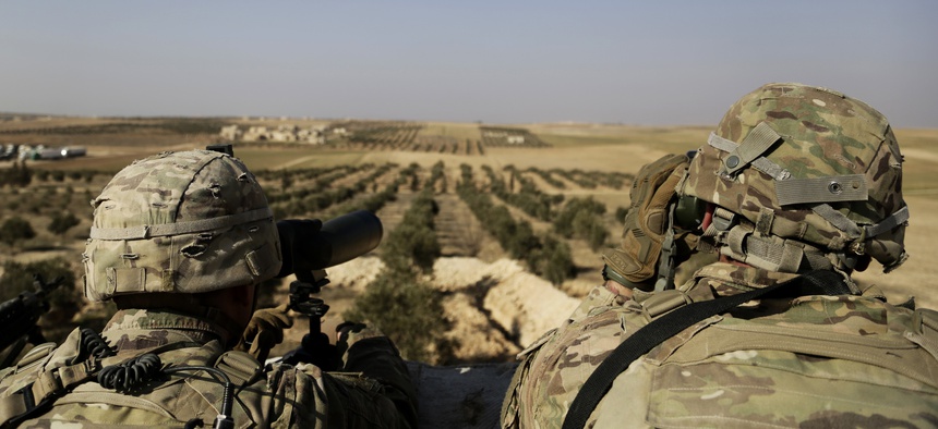 This Wednesday, Feb. 7, 2018 file photo, shows American troops looking toward the border with Turkey from a small outpost near the town of Manbij, northern Syria.