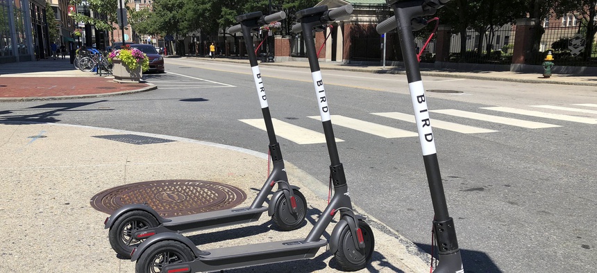 In this Friday, July 20, 2018 file photo, three dockless scooters stand on a sidewalk across the street from a Johnson & Wales University campus in downtown Providence, R.I.
