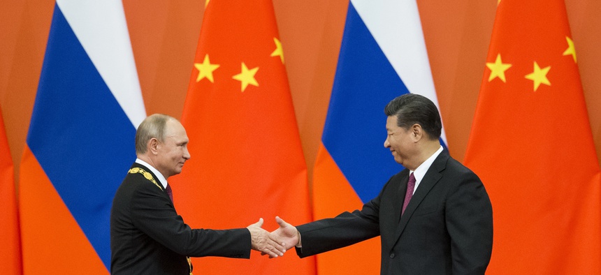 In this June 8, 2018, file photo, Chinese President Xi Jinping, right, and Russian President Vladimir Putin shake hands during an awarding ceremony at the Great Hall of the People in Beijing, China.
