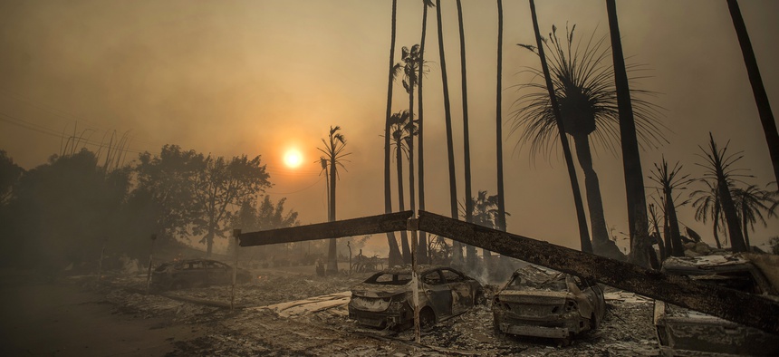 Smoke rises behind an apartment complex destroyed by fire in Ventura, California, December 5, 2017.
