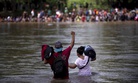 A migrant raises his fist as he nears the Mexican side of the the Suchiate River, that connects Guatemala and Mexico, Monday, Oct. 29, 2018.