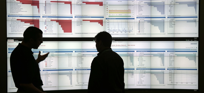 In this April 22, 2015 photo, Stijn Vanveerdeghem, left, an engineer with Cisco, shows graphics with live wireless traffic to FedEx employee Barry Poole during the RSA Conference in San Francisco.
