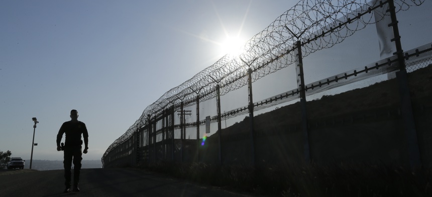 In this June 22, 2016, file photo, a Border Patrol agent walks along a border structure in San Diego, Calif.