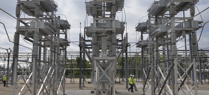 In this Wednesday, May 20, 2015 photo, contractors walk past a capacitor bank at an AEP electrical transmission substation in Westerville, Ohio.