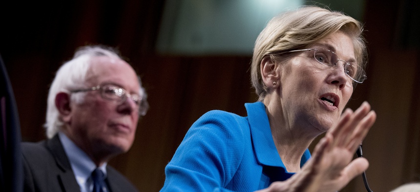 Sen. Elizabeth Warren, D-Mass., right, accompanied by Sen. Bernie Sanders, I-Vt., left, speaks during a news conference on Capitol Hill in Washington, Wednesday, Sept. 13, 2017.