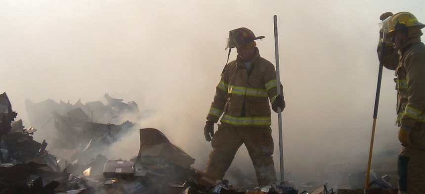 Two firefighters take a short break during a mop-up operation in a burn pit at a landfill on Forward Operating Base Speicher, near Tikrit, Iraq (IRQ), in support of Operation Iraqi Freedom.