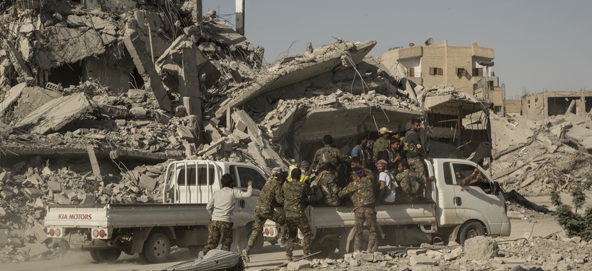 Members of the U.S.-backed Syrian Democratic Forces (SDF) ride near near the main traffic circle in Raqqa Syria, Friday, Oct. 20, 2017.