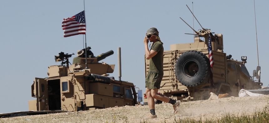 A U.S. soldier walks on a newly installed position, near the tense front line between the U.S-backed Syrian Manbij Military Council and the Turkish-backed fighters, in Manbij, north Syria, Wednesday, April 4, 2018.
