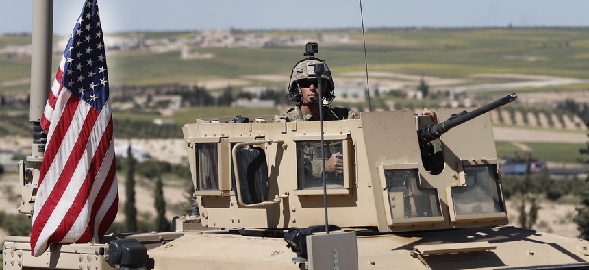 In this April 4, 2018 file photo, a U.S. soldier sits in an armored vehicle on a road leading to the tense front line with Turkish-backed fighters, in Manbij, north Syria.