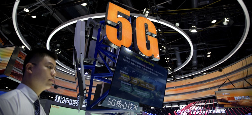A staff member stands at a display for 5G wireless technology from Chinese firm China Telecom at the PT Expo in Beijing, Wednesday, Sept. 26, 2018.