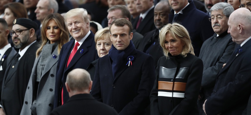 Russian President Vladimir Putin, back to camera, arrives to take his seat with French President Emmanuel Macron, Brigitte Macron, German Chancellor Angela Merkel, and U.S. President Donald Trump in Paris on Nov. 11, 2018.