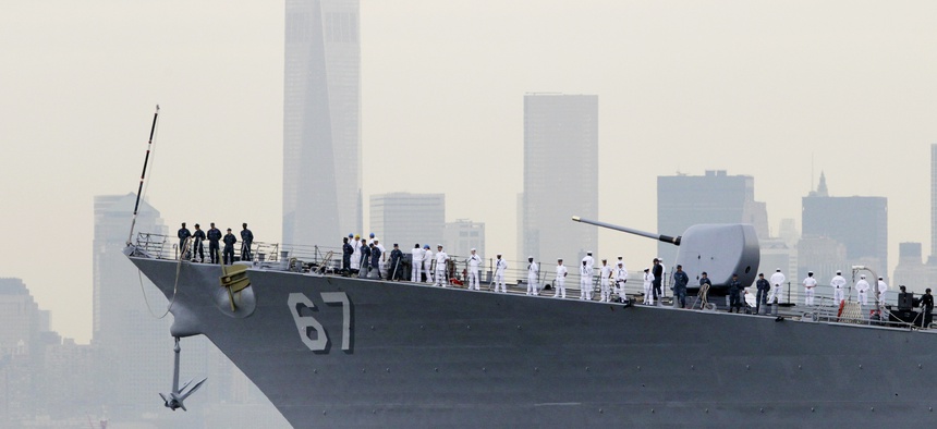 Sailors line the bow of the destroyer USS Cole as it glides past One World Trade Center and the lower Manhattan skyline, Wednesday, May 21, 2014 in New York.