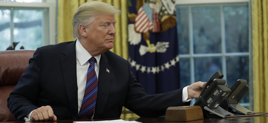 President Donald Trump makes a phone call in the Oval Office of the White House, Monday, Aug. 27, 2018, in Washington.