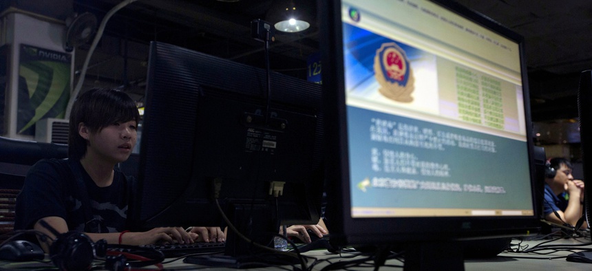 In this Aug. 19, 2013 file photo, computer users sit near a monitor display with a message from the Chinese police on the proper use of the Internet at an Internet cafe in Beijing, China.
