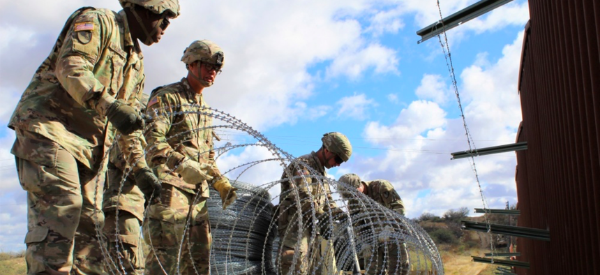 Engineers from 937th Clearance Company prepare to place concertina wire on the Arizona-Mexico border wall, Dec. 1, 2018.