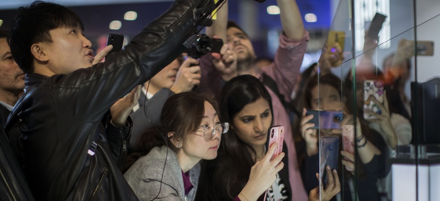 Attendees take pictures of the new Huawei Mate X foldable 5G smartphone during the Mobile World Congress wireless show, in Barcelona, Spain, Monday, Feb. 25, 2019.