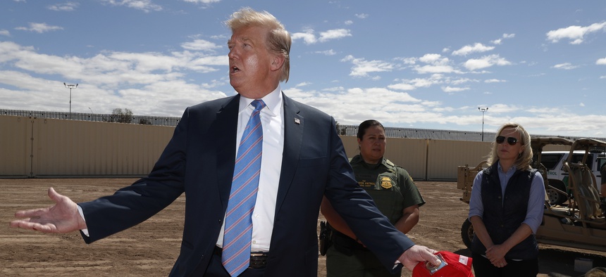 President Donald Trump visits a new section of the border wall with Mexico in Calexico, Calif., on April 5, 2019. Gloria Chavez with the U.S. Border Patrol, center, and Homeland Security Secretary Kirstjen Nielsen listen.