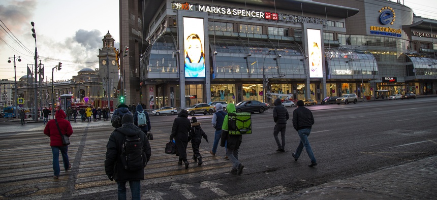 People cross the street in front of the Evropeisky shopping center, in Moscow, Russia, Wednesday, Nov. 28, 2018.