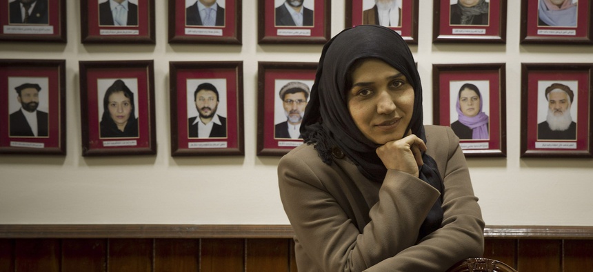 In this 2014 photo, Afghan lawmaker Habiba Danish from Takhar poses next to the picture wall showing Afghanistan’s 249 parliamentarians in the parliament in Kabul.