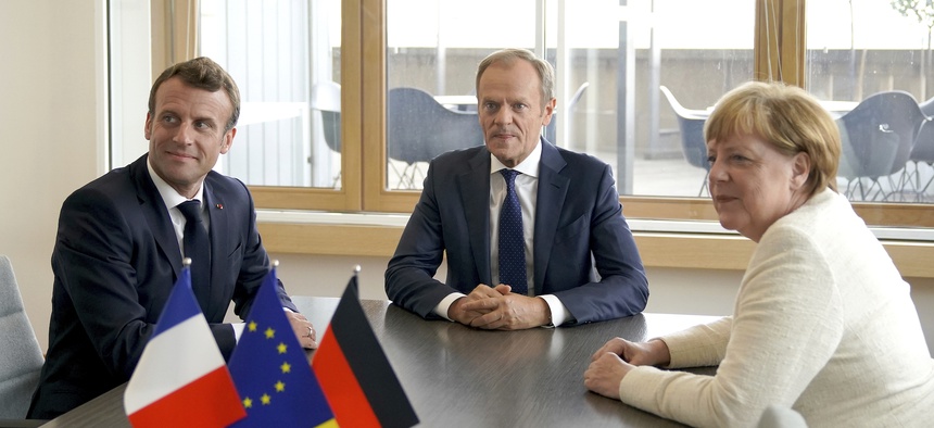 European Council President Donald Tusk, center, and German Chancellor Angela Merkel meet on the sidelines of an EU summit in Brussels, Thursday, June 20, 2019
