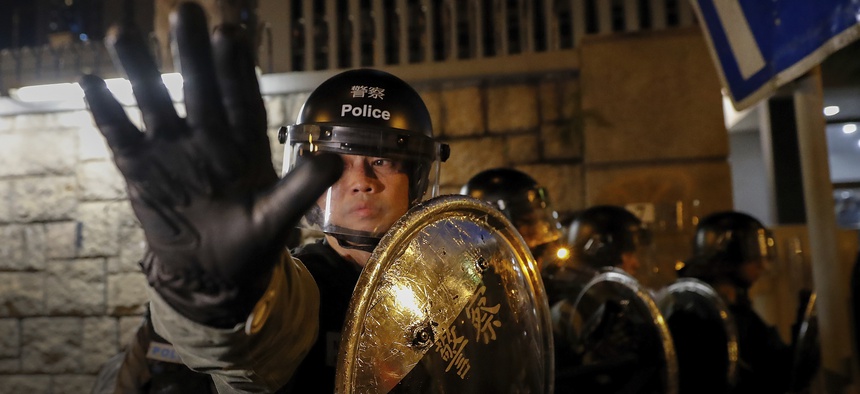 A riot policeman gestures as they retreat back to Kwun tong police station in Hong Kong, Sunday, Aug. 4, 2019.