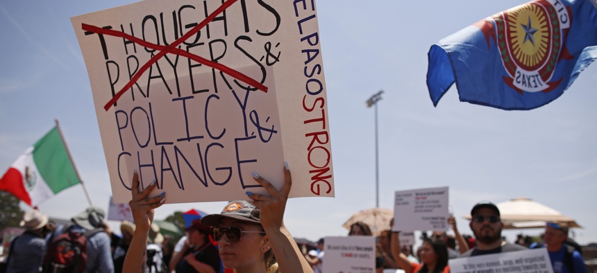 Marisela Hernandez holds sign to protest the visit of President Donald Trump to the border city after the Aug. 3 mass shooting in El Paso, Texas, Wednesday, Aug. 7, 2019.