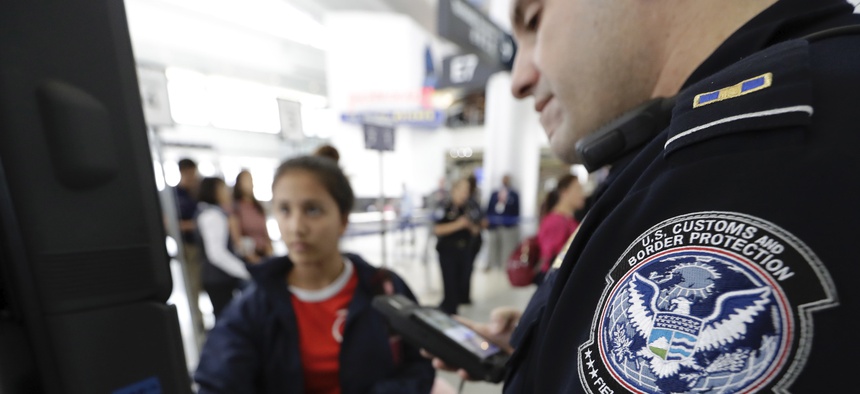 A U.S. Customs and Border Protection officer helps a passenger navigate a new facial recognition kiosk before boarding a flight to Tokyo in 2017 at George Bush Intercontinental Airport, in Houston.