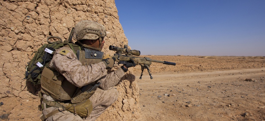 U.S. Marine Cpl. Dennis Cox, a scout sniper assigned to 1st Battalion, 9th Marine Regiment, Regional Command (Southwest), inches closer to the edge of a dirt wall during an interdiction operation in Helmand province, Afghanistan, Dec. 19, 2013.