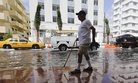 In this 2015 photo, Louis Fernandez walks along a flooded street in Miami Beach, Fla.
