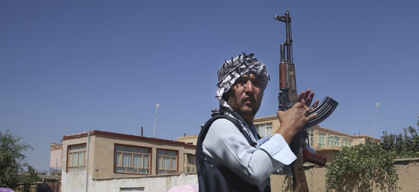 An Afghan volunteer stands guard outside a mosque during a memorial service for the victims of the Dubai City wedding hall bombing in Kabul, Afghanistan, Tuesday, Aug. 20, 2019.