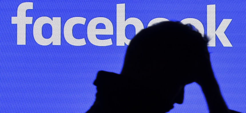 A man passes a facebook screen at the Gamescom in Cologne, Germany, Tuesday, Aug. 20, 2019.