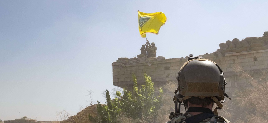 In this Sept. 21, 2019, photo, a U.S. soldier watches the Syrian Democratic Forces demolish a Kurdish fighters' fortification and raise a Tal Abyad Military Council flag over the outpost as part of the so-called "safe zone" near the Turkish border.