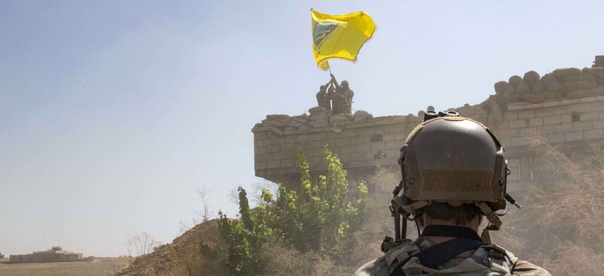 A U.S. soldier oversees members of the Syrian Democratic Forces, or SDF, demolishing a Kurdish fighters' fortification and raising a Tal Abyad Military Council flag as part of the "safe zone" near the Turkish border, Sept. 21, 2019.