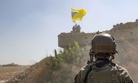 A U.S. soldier oversees members of the Syrian Democratic Forces, or SDF, demolishing a Kurdish fighters' fortification and raising a Tal Abyad Military Council flag as part of the "safe zone" near the Turkish border, Sept. 21, 2019.