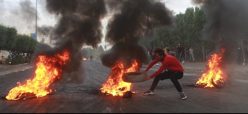 Anti-government protesters set fires and close a street during a demonstration in Baghdad, Iraq, Sunday, Oct. 6, 2019.