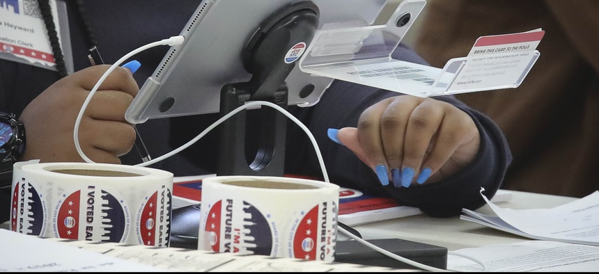 A new E-Poll Book tablet is used to process a voter, during early voting at Brooklyn's Clara Barton High School, Saturday Oct. 26, 2019, in New York.