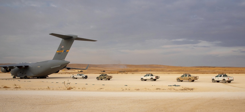 In this Oct. 25, 2019, photo, pickup trucks line up to be loaded onto a cargo plane at the Kobani Landing Zone (KLZ), part of coalition forces' withdrawal from northern Syria.