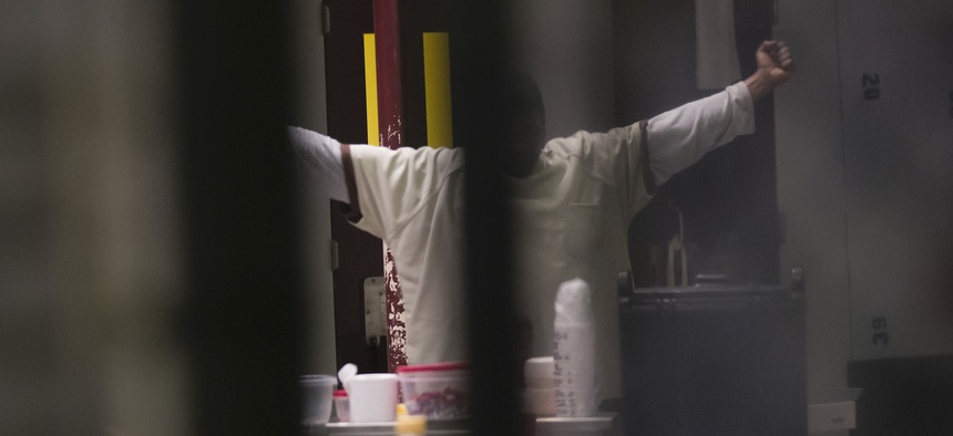 In this photo reviewed by U.S. military officials, a detainee, name and facial identification not permitted, stretches inside the Camp VI detention facility, Wednesday, April 17, 2019, in Guantanamo Bay Naval Base, Cuba.