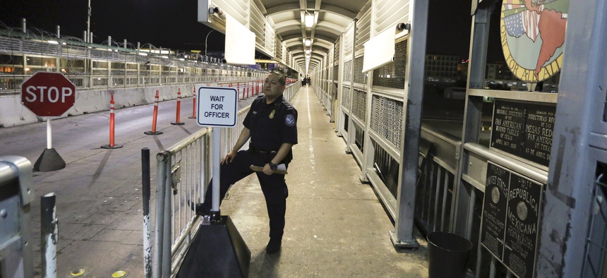 A U.S. Customs and Border Protection officer waits for migrants who are applying for asylum in the United States to arrive at International Bridge 1 where they will cross from Nuevo Laredo, Mexico, to Laredo, Texas, early Tuesday, Sept. 17, 2019.