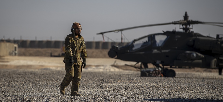 A crewman walks past an attack helicopter at a US military base at an undisclosed location in eastern Syria, Monday, Nov. 11, 2019.