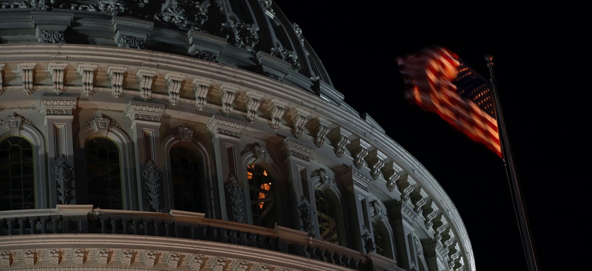 An American flag flutters in the wind in front of the U.S. Capitol dome in Washington, late Tuesday, Nov. 12, 2019.