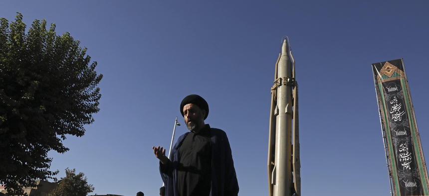A Muslim cleric walks in downtown Tehran, where a Shahab-3 surface-to-surface missile is on display on Sept. 25, 2019.