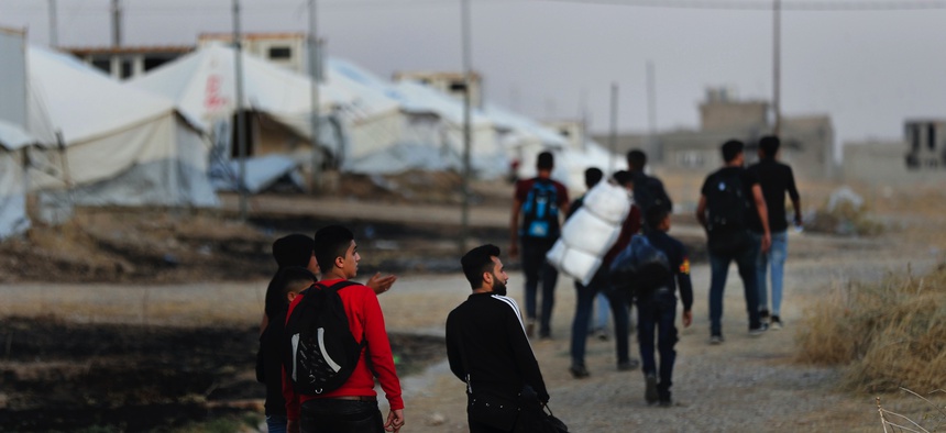 Syrians who were displaced by the Turkish military operation in northeastern Syria carry their belongings as they arrive at the Bardarash refugee camp, north of Mosul, Iraq, Thursday, Oct. 17, 2019.