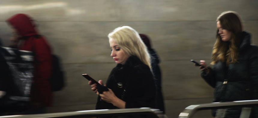 Women use their smartphones wile walking in Moscow's subway, Russia, Monday, Dec. 23, 2019.
