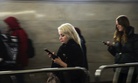 Women use their smartphones wile walking in Moscow's subway, Russia, Monday, Dec. 23, 2019.