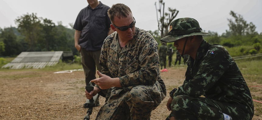 U.S. Marine Corps Staff Sgt. Gabriel T. Green, a platoon sergeant with 9th assists Thai soldiers with a metal detector during survey training event at the Charumanee Training Field in Ratchaburi, Kingdom of Thailand, Dec. 18, 2018.