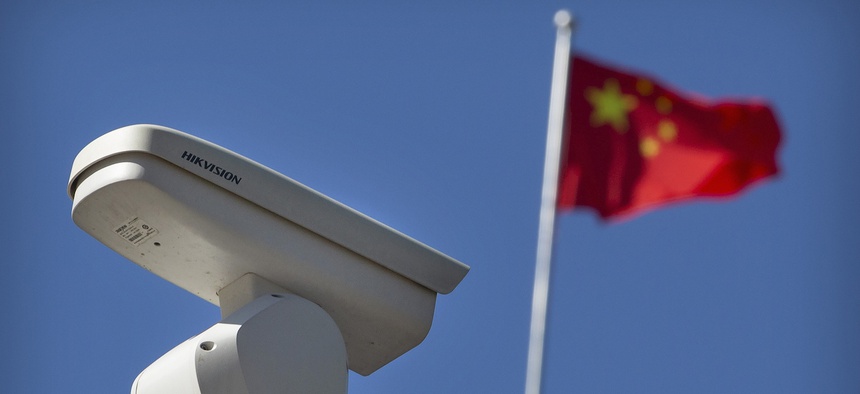 A Chinese flag flies near a Hikvision security camera monitoring a traffic intersection in Beijing, Tuesday, Oct. 8, 2019
