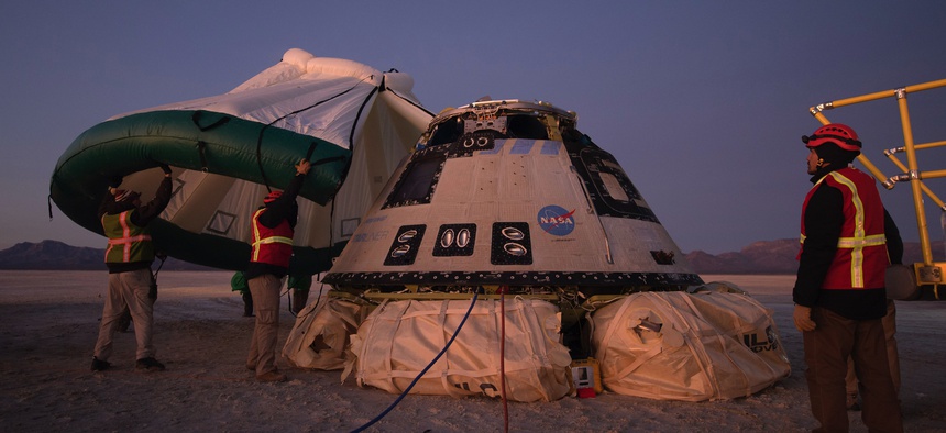 Boeing, NASA, and U.S. Army personnel work around the Boeing Starliner spacecraft shortly after it landed in White Sands, N.M., on Dec. 22, 2019.