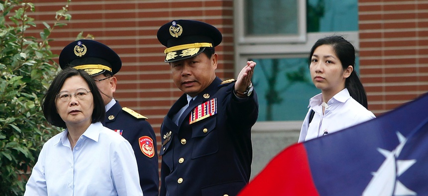 Taiwan's President Tsai Ing-wen, left, walks past a Taiwan national flag during an offshore anti-terrorism drill outside the Taipei harbor in New Taipei City, Taiwan, Saturday, May 4, 2019.